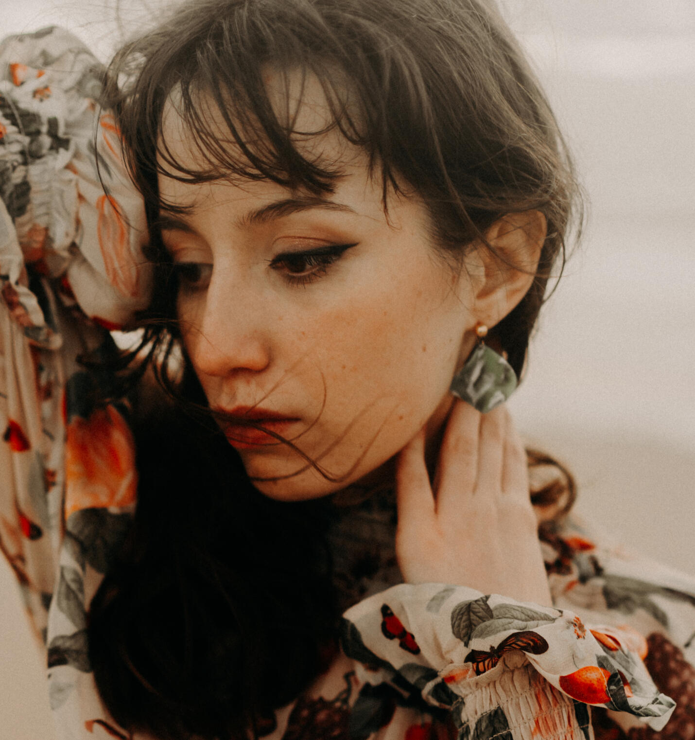 close up picture of a women wearing green floral dangle earrings in green